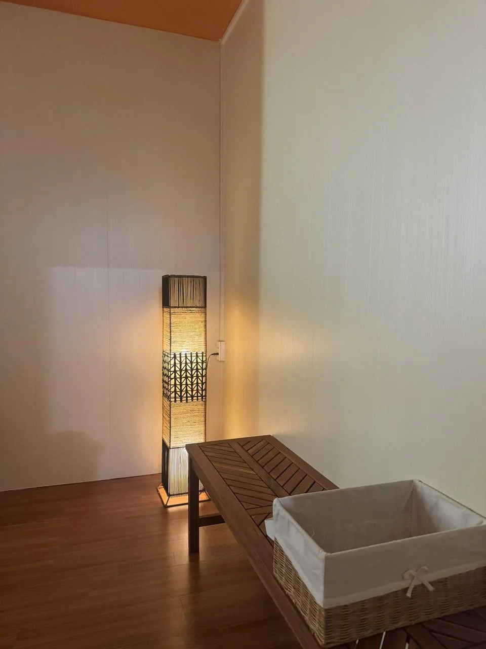 Đèn mây cạnh ghế gỗ và giỏ vải tại AnRohi